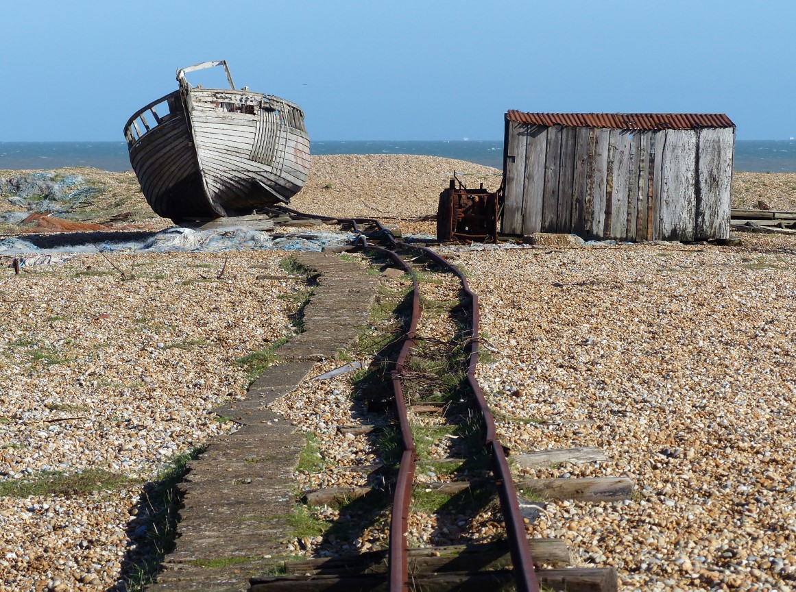 Old boat and rail track on a shingle beach